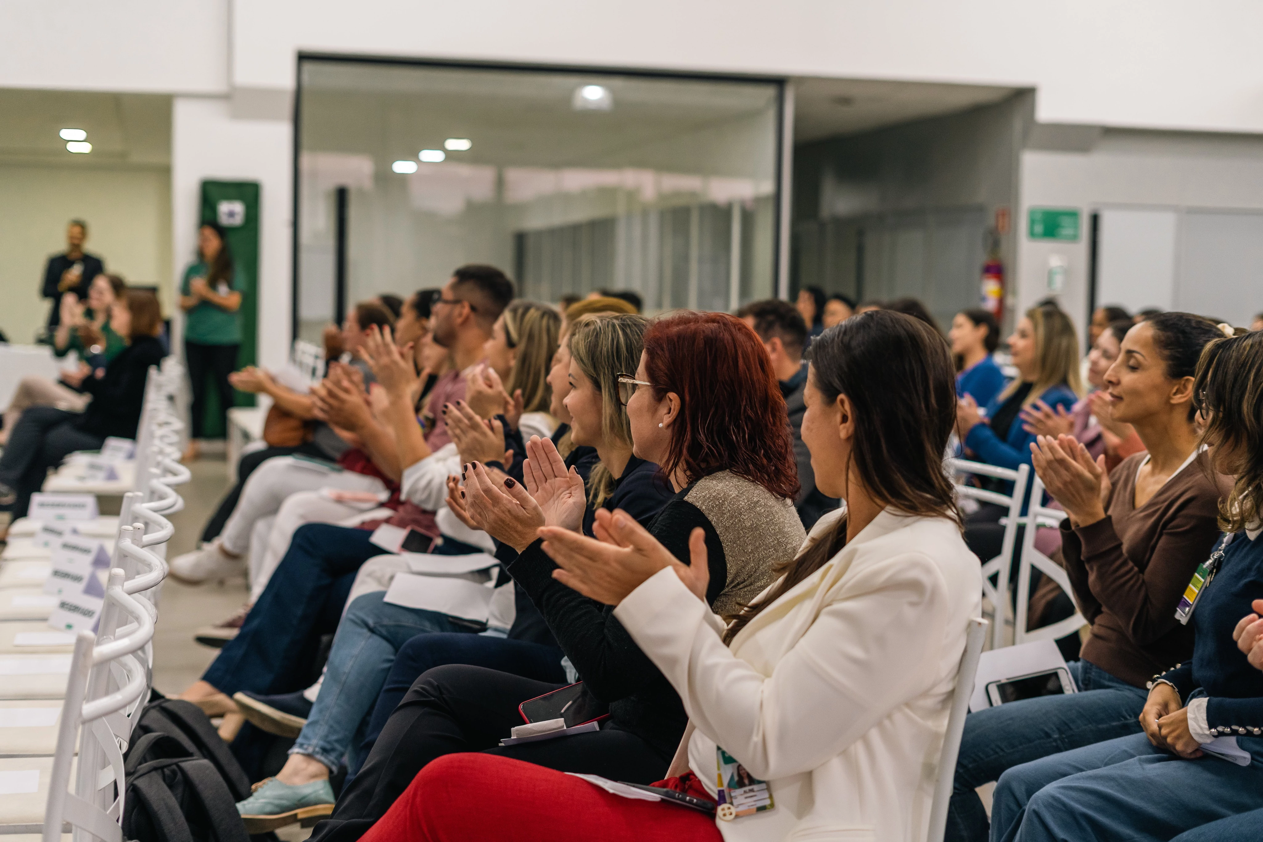 People sitting and clapping in a conference room.